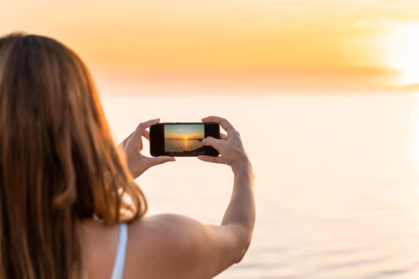 Young woman photographing sunset