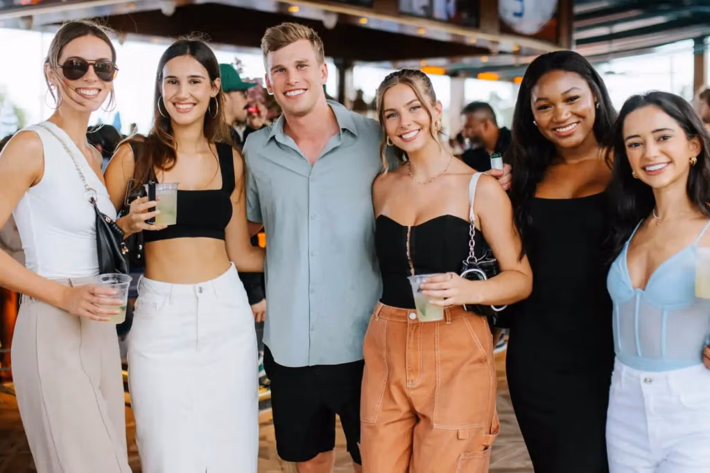 A group of six young adults smiling together at a Regatta Grove event.